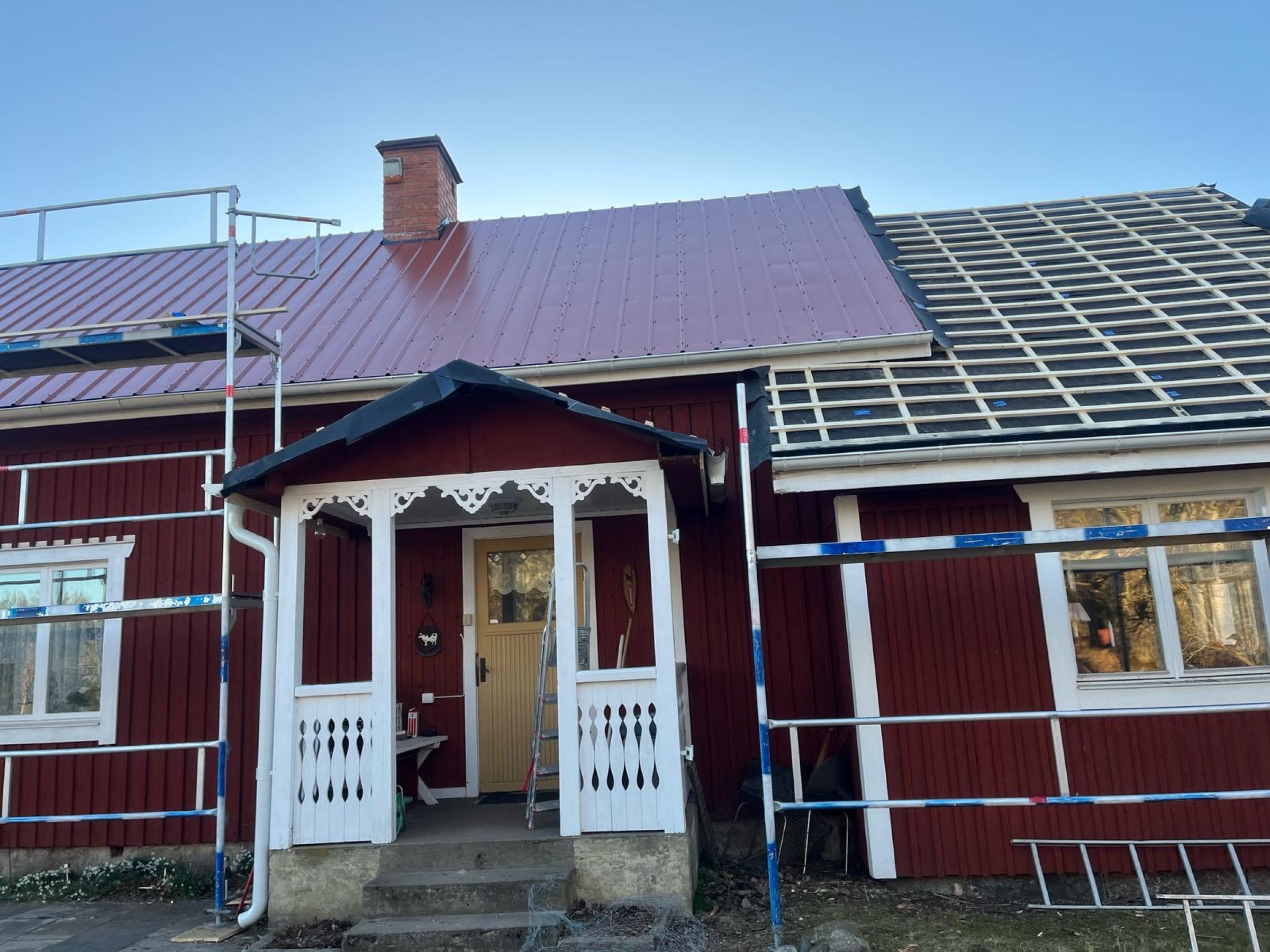 Fasadställning vid röd torpstuga under pannplåtsbyte